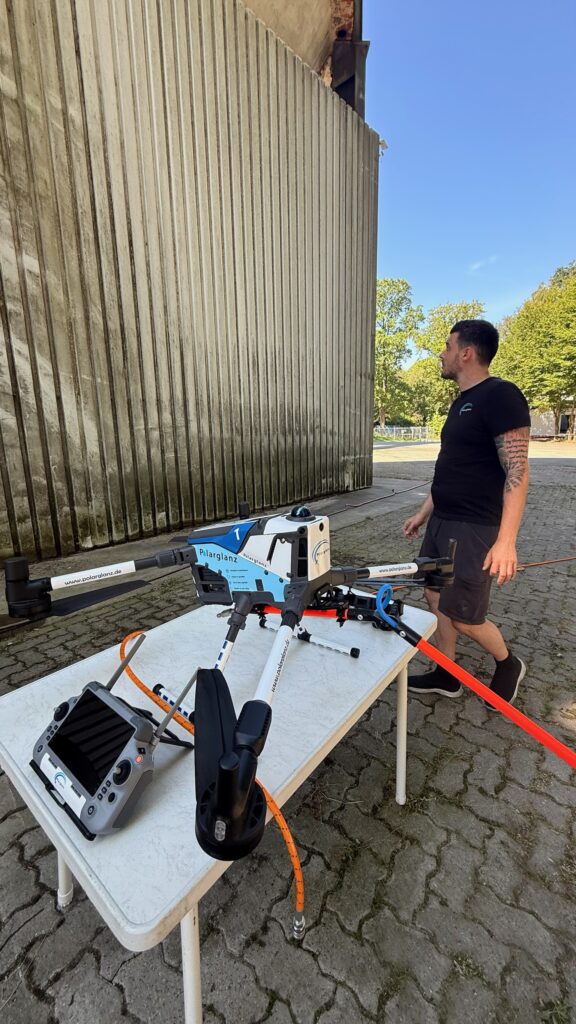 Ian Krüger von Polarglanz neben der Reinigungsdrohne Matrice 400R, die Drohne ist etwa so breit wie ein Tisch